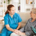 Female nurse having a conversation with pensioner woman in nursing home.