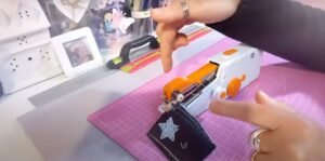 Gros plan d'une machine à coudre portable utilisée pour ajouter des coutures à une création de scrapbooking.