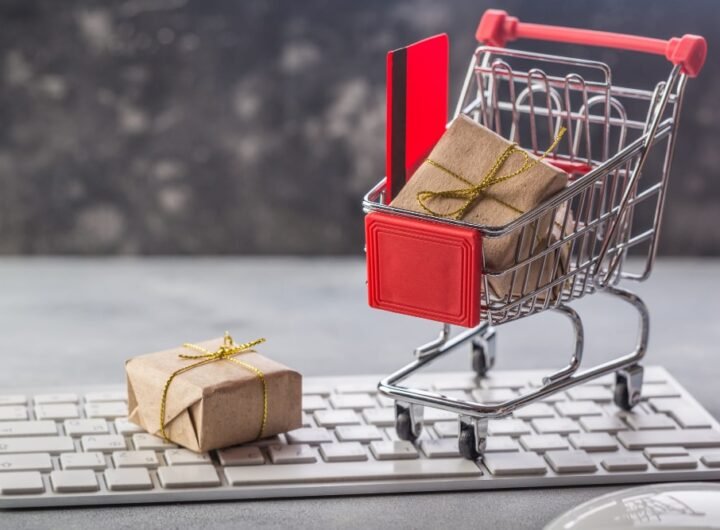 Un mini-chariot de courses contenant un cadeau et une carte, posé sur un clavier, évoquant le shopping en ligne Temu.